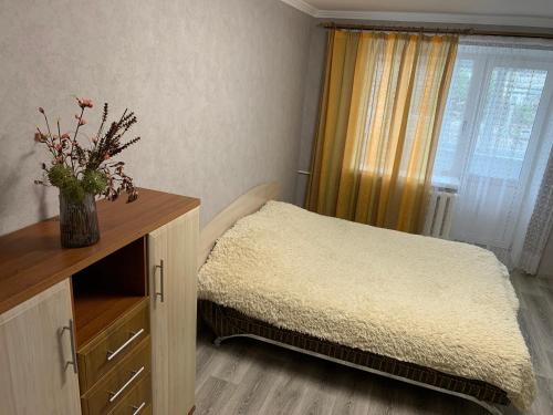 a bedroom with a bed and a dresser with a window at APARTMENT PREMIUM VIP in Berdychiv
