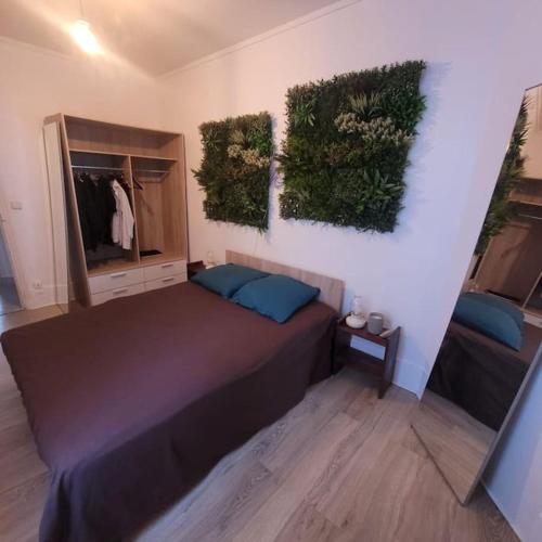 - une chambre avec un grand lit et des plantes sur le mur dans l'établissement La Fourche, à Paris