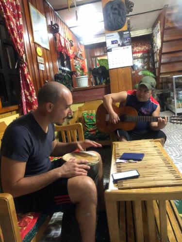 two men sitting at a table playing a guitar at Las vegas lodge and restaurant in Banaue