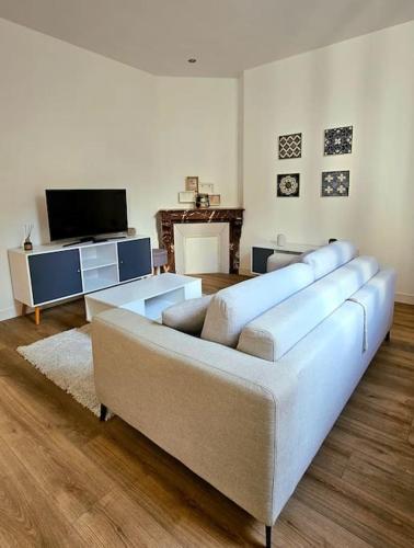 a living room with a couch and a tv at La Perle Bleue in Compiègne