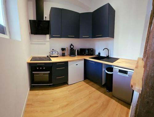 a kitchen with black cabinets and a wooden floor at La Perle Bleue in Compiègne