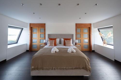 a bedroom with a large bed with two windows at Woodside Barn Stunning 7 bed Barn conversion in Newmachar