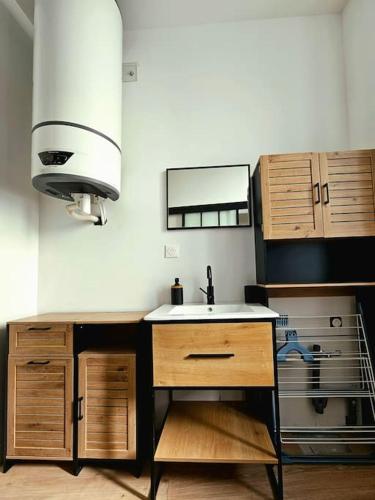 a kitchen with a sink and wooden cabinets at La Perle Bleue in Compiègne