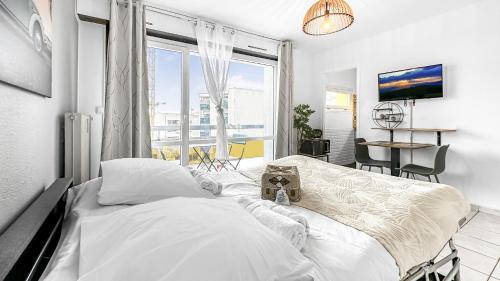 une chambre blanche avec un lit et une grande fenêtre dans l'établissement HOMEY MOSA - Au pied du Tram - Proche centre - Balcon Privé - Wifi et Netflix, à Annemasse