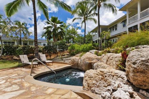a swimming pool with a waterfall in a yard with palm trees at Coconut Plantation 1086-4 in Kapolei