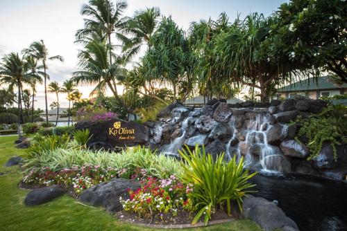 a waterfall in a park with flowers and palm trees at Coconut Plantation 1086-4 in Kapolei