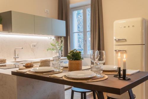 a kitchen with a table with wine glasses and a refrigerator at V Suite on Lake Como By Rent All Como in Como