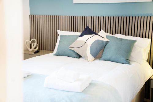 a white bed with blue and white pillows on it at NEW! 4BR in Stafford Place in Peterlee