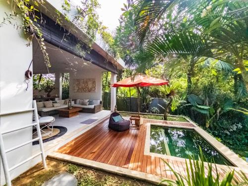 an outdoor patio with a pool and an umbrella at Silversand Villa in Tanah Lot