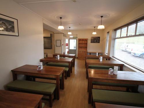 a dining room with wooden tables and green chairs at YHA Snowdon Llanberis in Llanberis