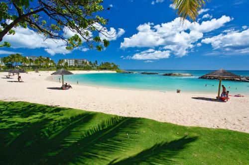a beach with people and umbrellas and the ocean at Coconut Plantation 1214-2 Aloha Lagoons in Kapolei
