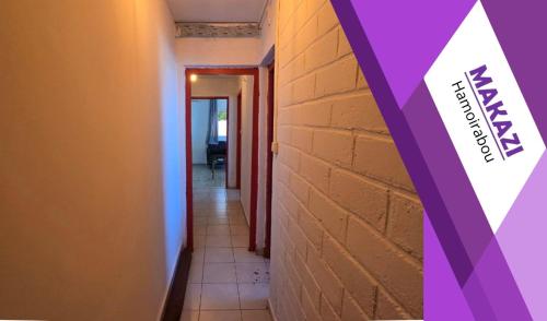 a hallway with a brick wall and a sign on it at MAKAZI Hamoirabou in Tsingoni