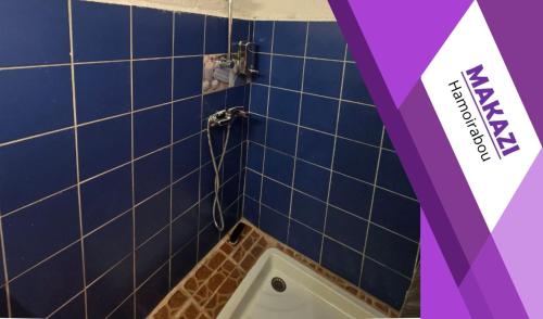 a blue tiled bathroom with a bath tub in it at MAKAZI Hamoirabou in Tsingoni