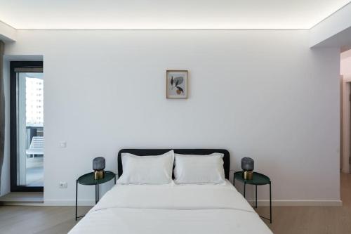 ein weißes Schlafzimmer mit einem Bett und zwei Tischen in der Unterkunft Ironcrest Studio - Cortina in Voluntari