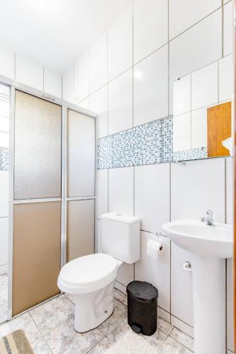a white bathroom with a toilet and a sink at Pousada Luna in Socorro