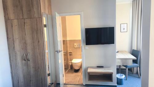 a room with a bathroom with a toilet and a television at Hotel St.-Michaels-Heim in Berlin