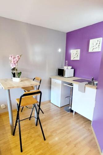 Il comprend une cuisine avec une table et des chaises ainsi qu'une cuisine pourpre. dans l'établissement Studio Pause détente à Corbas accès Piscine, confort & tranquillité, à Corbas