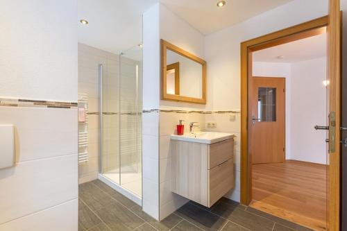 ein Badezimmer mit Waschbecken, Dusche und Spiegel in der Unterkunft Schusterhof Urlaub auf dem Bauernhof in Bernau am Chiemsee