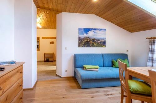 ein Wohnzimmer mit einem blauen Sofa und einem Tisch in der Unterkunft Schusterhof Urlaub auf dem Bauernhof in Bernau am Chiemsee