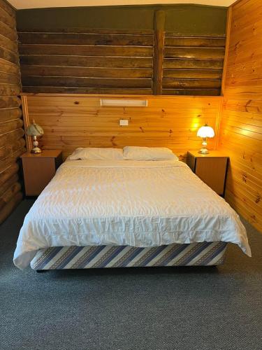 a bedroom with a large bed with wooden walls at Lakes Entrance Log Cabins in Lakes Entrance