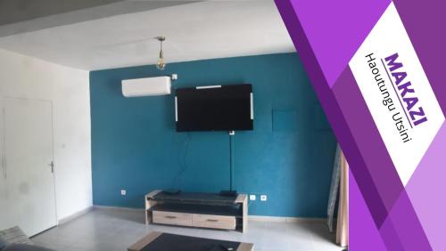 a living room with a blue wall and a tv at MAKAZI Haoutoungou in Combani