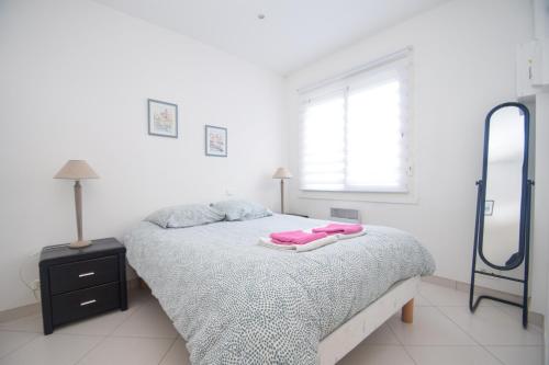 une chambre blanche avec un lit et un miroir dans l'établissement Appt 2 pièces confort 3 pers au pied de la plage vacances sans voiture, à Dinard