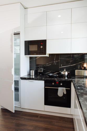 a white kitchen with a stove and a microwave at Penthouse Vacation in Moldova! in Chişinău