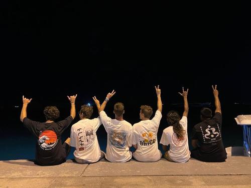 a group of people sitting on the ground with their hands in the air at Konut by Thakuru in Guraidhoo