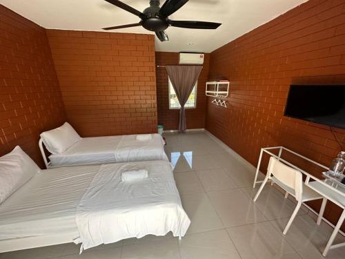 a bedroom with two beds and a flat screen tv at Chalet Siti Balqis in Masjid Tanah