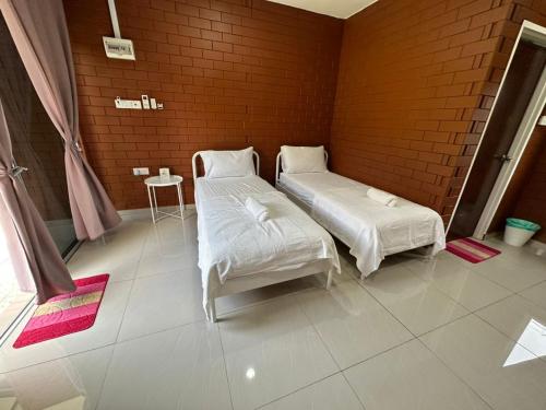 two beds in a room with a brick wall at Chalet Siti Balqis in Masjid Tanah