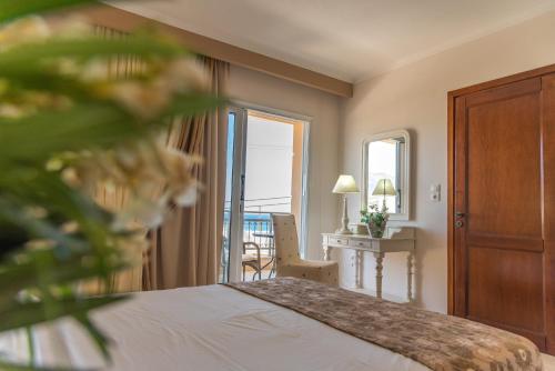 a bedroom with a bed and a table with a chair at Hotel Astron Princess in Karpathos Town