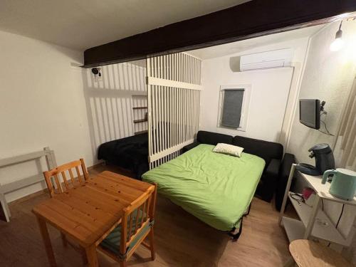 - une petite chambre avec un lit vert et une table dans l'établissement Studio Cosy hyper centre Aix, à Aix-en-Provence