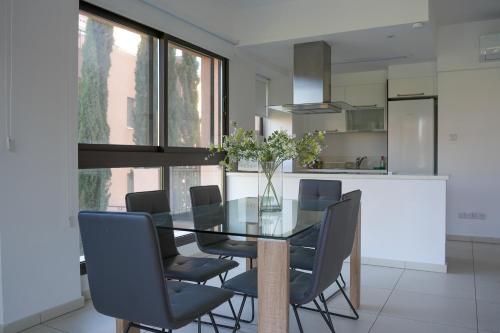 a dining room with a glass table and chairs at Resitour - Aphrodite Gardens in Paphos City