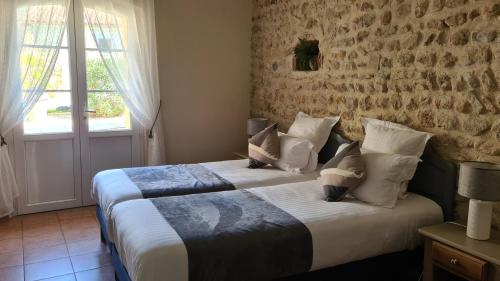 a bedroom with two beds and a brick wall at Logis Hôtel La Bastide Saint Bach in Suze-la-Rousse