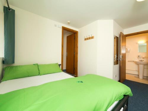 a bedroom with a large bed with green sheets at YHA Brecon Beacons in Brecon