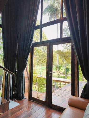 a room with a large glass door with curtains at Cheewatra Farmstay Phuket ชีวาตรา ฟาร์มสเตย์ ภูเก็ต in Thalang