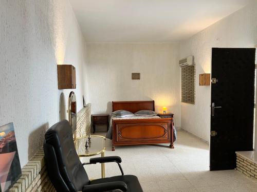 een slaapkamer met een bed, een bureau en een stoel bij Dar Othmen in Tozeur