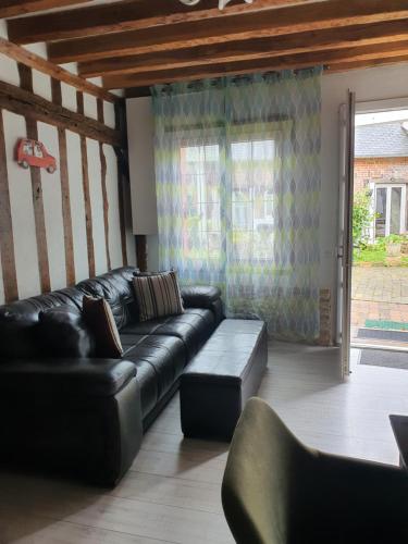 - un salon avec un canapé en cuir noir et une fenêtre dans l'établissement Maison Normandie, à Glos-sur-Lisieux