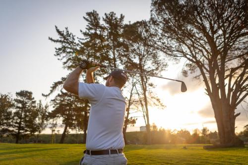 a man swinging a golf club on a golf course at Devonvale Golf & Wine Estate in Stellenbosch