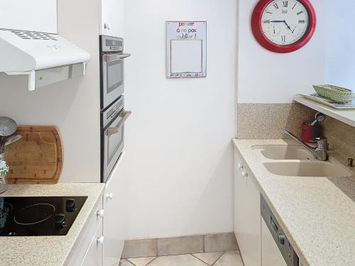 une cuisine avec un évier et une horloge murale dans l'établissement Bel appartement à 2 pas des plages 151L DEBL, à Cannes