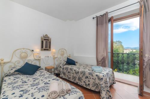 Un dormitorio con dos camas y un balcón. en Residenza le Giare, en La Maddalena