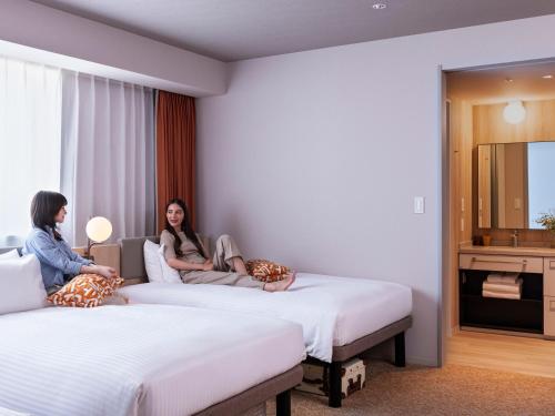 two women sitting on beds in a hotel room at Mitsui Garden Hotel Ginza Tsukiji in Tokyo