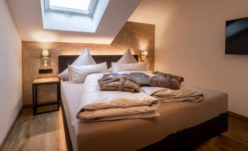 a bedroom with a bed with white sheets and a window at FOR MOMENTS Apartments & Spa in Roßhaupten