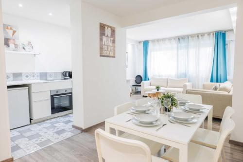 Il dispose d'une cuisine blanche et d'un salon avec une table et des chaises blanches. dans l'établissement Magnificent apartment - 2BR-6P - Levallois-Perret, à Levallois-Perret