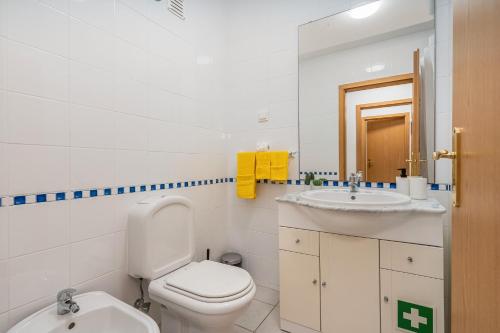 a white bathroom with a toilet and a sink at Sea Breeze in Portimão