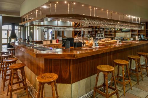 a bar with wooden stools in a restaurant at Devonvale Golf & Wine Estate in Stellenbosch