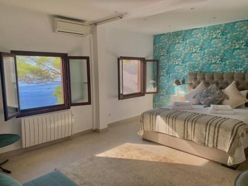 sypialnia z łóżkiem i dużym oknem w obiekcie Maripins Villa con jacuzzi y vistas únicas al mar w mieście Banyalbufar