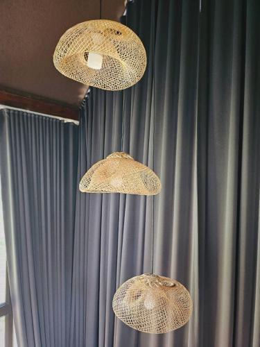 three lights hanging from the ceiling in front of a curtain at Cheewatra Farmstay Phuket ชีวาตรา ฟาร์มสเตย์ ภูเก็ต in Thalang