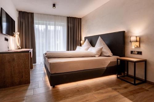 a bedroom with a bed and a large window at FOR MOMENTS Apartments & Spa in Roßhaupten