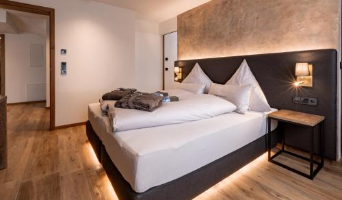 a bedroom with a large white bed with a wooden headboard at FOR MOMENTS Apartments & Spa in Roßhaupten
